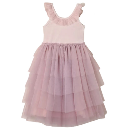 The Girls’ Pixie Dress by Noralee is a sleeveless, light pink dress featuring a luxurious velvet bodice, a ruffled neckline, and a tiered tulle skirt, displayed against a white background.