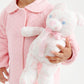 A young child in a pink quilted jacket holds the Bradley Bear - Sir Propers Sweet Arrival, a white teddy bear with pink patterns and a pink ribbon from The Beaufort Bonnet Company—an adorable companion that would make the perfect baby shower gift.