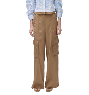 Person wearing Simkhai's Ivrie Utility Pant—tan, wide-leg cargo pants with multiple pockets—paired with a blue striped shirt, standing against a white background.