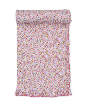 The Kissy Kissy Ruffle Blanket, featuring a charming floral pattern and pink ruffled edges, is shown partially rolled out on a white background—perfect for wrapping a little girl in cozy comfort.