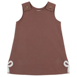 Sleeveless brown Girls’ Juliet Jumper toddler dress from The Beaufort Bonnet Company, crafted from soft Pima Cotton Knit with buttoned shoulder straps and white bow accents at the bottom corners, laid flat against a white background—a charming piece for little ones.