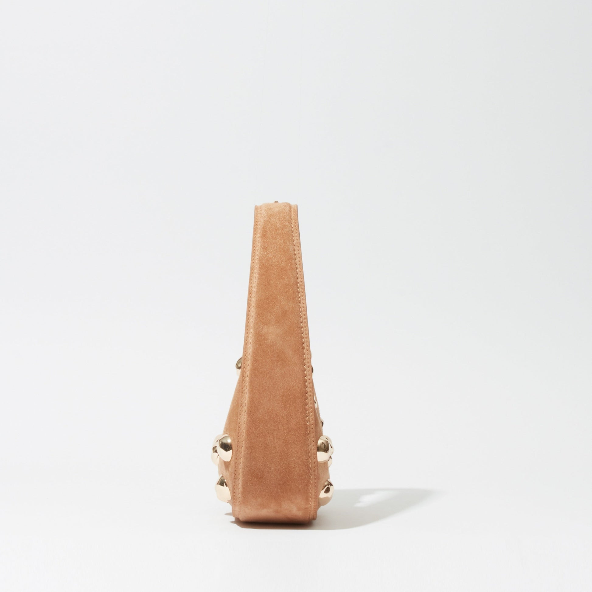 Side view of the Simkhai Finn Studded Suede Shoulder Bag in tan, featuring gold stud embellishments, photographed against a plain white background.