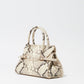 The Simkhai River Small Snake Top Handle Bag features beige and brown snakeskin, two top handles, and a decorative belt detail, shown against a plain white background.