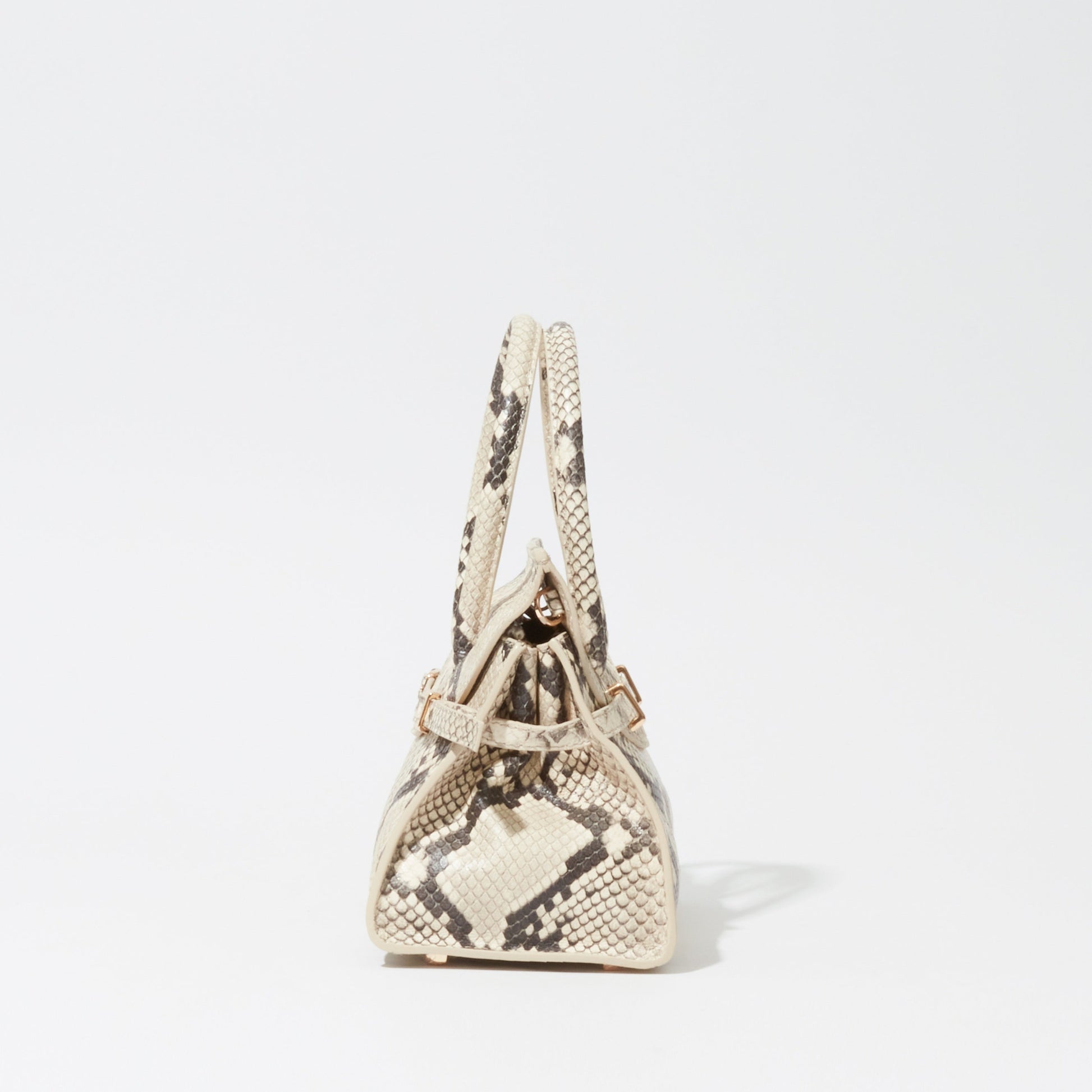 Side view of the Simkhai River Small Snake Top Handle Bag in beige with a snake print, structured triangular shape, and top handle, shown against a plain white background.