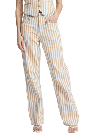 A person wearing Rag & Bone's Shea High-Rise Relaxed Straight Full Length Stripe pants in beige and white stands with one hand in their pocket, paired with an matching vest and open-toe sandals.