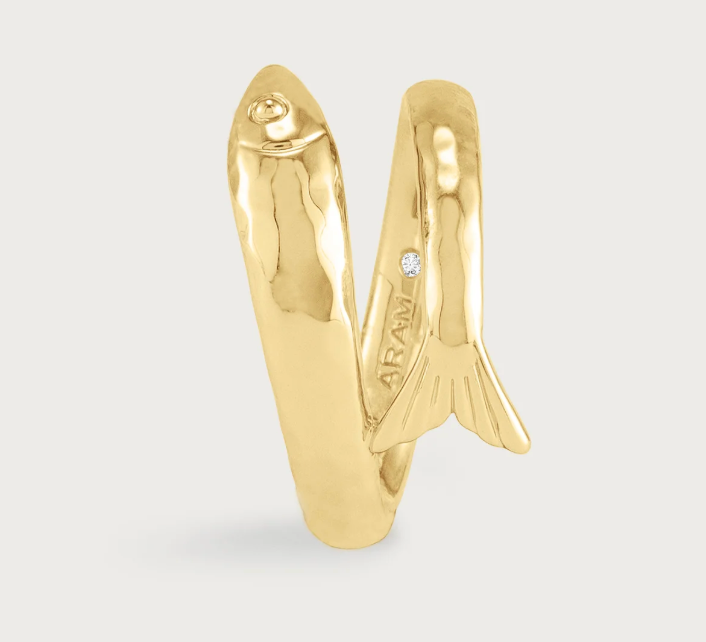 The Milos Fish Ring is an 18K gold plated bypass ring shaped like a fish, featuring a small inset stone near the tail.