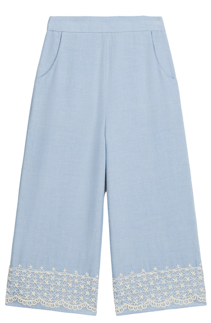 The Girls’ Florelia Pants by Louise Misha are light blue wide-leg Oxford cotton trousers with pockets, an elasticized waist, and delicate white embroidered lace detail along the hem.