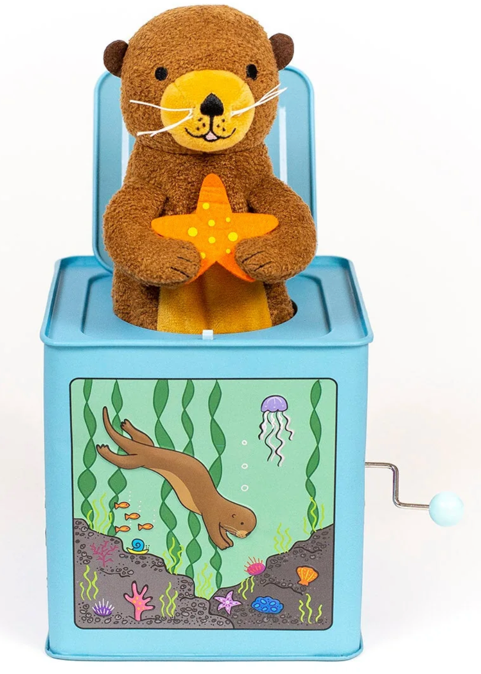 The Jack-in-the-Box by Jack Rabbit Creations features a plush otter holding a starfish that pops out of a blue box decorated with an underwater scene and an otter illustration—ideal for anyone who loves cute plush characters.