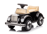 Black and beige children’s ride-on toy car featuring chrome accents, a large steering wheel, and a “300S” license plate, displayed on a white background. The Freddo Mercedez Benz 300S Mini Ride-On blends classic style with playful details, making it the ideal 6V mini ride-on for young drivers.