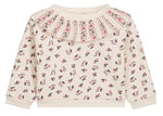 The Louise Misha Baby Girls’ Rosaline Sweatshirt is a long-sleeve, cream-colored piece for toddlers, featuring a ruffle neckline, pleated details, and delicate pink floral accents for a soft, charming look.