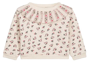 The Louise Misha Baby Girls’ Rosaline Sweatshirt is a long-sleeve, cream-colored piece for toddlers, featuring a ruffle neckline, pleated details, and delicate pink floral accents for a soft, charming look.