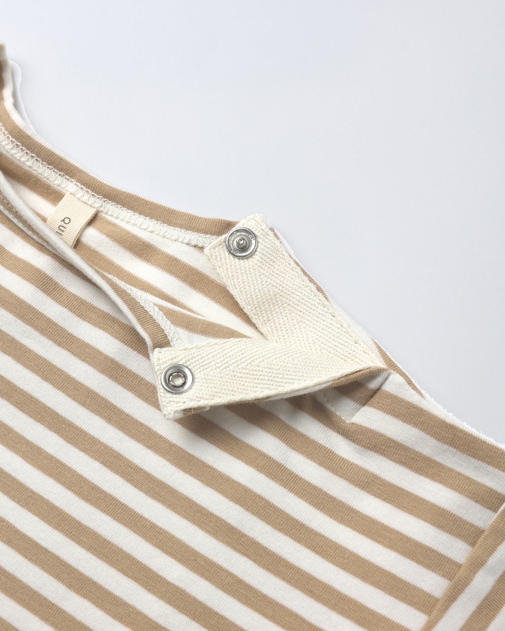 Close-up of the Quincy Mae Baby Boys' Long Sleeve Pocket Jumpsuit in beige and white stripes, featuring two metal snap buttons on the shoulder flap for easy changing.