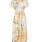The Aire Maxi Dress by Agua By Aguabendita features a long, short-sleeved silhouette with a cinched waist and a light floral print in yellow, orange, green, and white, accented with delicate hand-embroidered details.