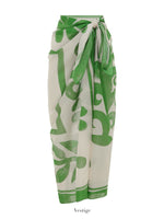 The Soleil Soleil Square Pareo by Soleil Soleil is a beige and green wrap skirt featuring a large abstract floral print, styled with a front knot—ideal as an organic cotton beach cover-up.