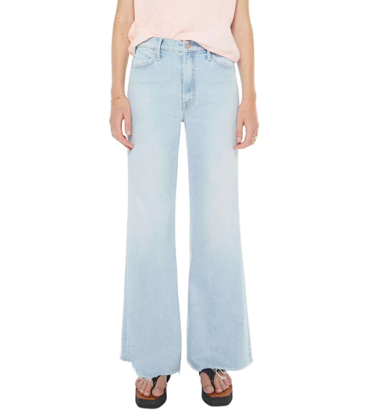 A person wearing The Hustler Roller Skimp Fray high-rise light blue wide-leg jeans by Mother, paired with a sleeveless light pink top, platform sandals, and minimal jewelry, stands against a white background.