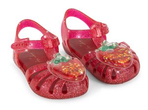 The Girls’ Lilo Sandal by Konges Slojd features a playful design with pink glitter jelly material, ankle straps, and large heart-shaped strawberry decorations on the toes. These glittery beach sandals offer both comfort and style for sunny days, complete with an easy Velcro closure inspired by the charming signature look of Konges Slojd—making them perfect for little feet.