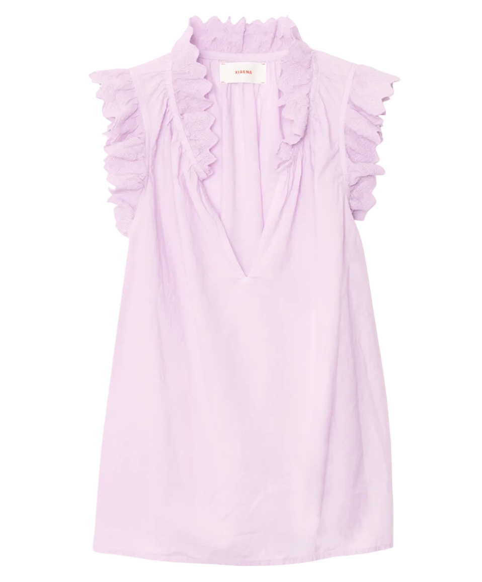 The Bexie Top by Xirena is a sleeveless light purple popover with a deep V-neckline and ruffled collar, crafted from lightweight fabric for an airy feel.