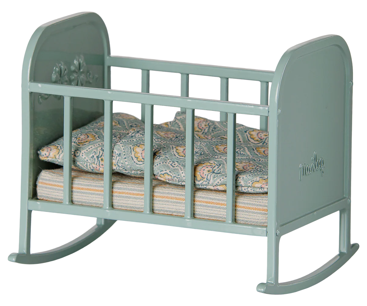 Blue Mint Cradle - My by Maileg: A small blue mint toy rocking cradle with side rails, delicate floral decorations, and patterned bedding inside, shown from a slight angle. It features gentle rocking legs and comes complete with a cozy sleeping bag—perfect for pretend play.