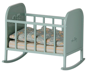 Blue Mint Cradle - My by Maileg: A small blue mint toy rocking cradle with side rails, delicate floral decorations, and patterned bedding inside, shown from a slight angle. It features gentle rocking legs and comes complete with a cozy sleeping bag—perfect for pretend play.