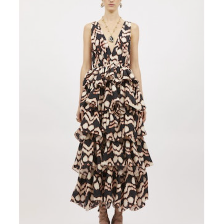 A person wearing the Ulla Johnson Dephne Dress, a sleeveless V-neck silk taffeta gown with a bold abstract black and beige pattern and ruffled maxi skirt, stands against a plain white background.
