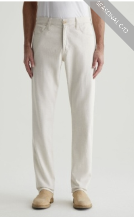 A person wearing the Everett Slim Straight off-white twill linen pants by AG Jeans, featuring a mid-rise waist and straight-leg fit, paired with tan shoes and standing against a plain background. A "SEASONAL C/O" banner appears in the top right corner.