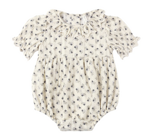 The Rylee & Cru Baby Girls’ Liv Romper features a vintage-inspired cream color, short puffed sleeves, a delicate ruffled scalloped collar, and an all-over small floral print pattern.