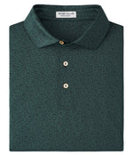The Peter Millar No Slow Play Performance Jersey Polo is a dark green, short-sleeve polo with a subtle pattern, three buttons, and an inside collar label, crafted for four-way stretch and UPF 50+ protection.