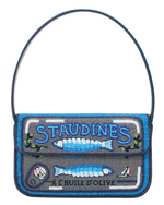 The Tommy Beaded Bag by Staud is a vegan leather handbag designed to look like a sardine tin, featuring blue, silver, and black beads, "STAUDINES" text, and fish images on the front.