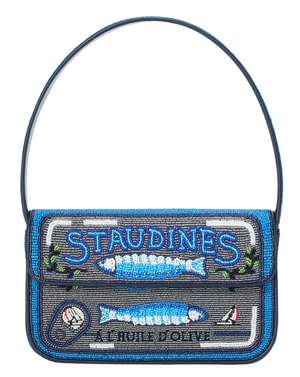 The Tommy Beaded Bag by Staud is a vegan leather handbag designed to look like a sardine tin, featuring blue, silver, and black beads, "STAUDINES" text, and fish images on the front.
