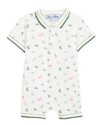 The Tartine et Chocolat Baby Boys’ Short Jumpsuit is a short-sleeve cotton romper with a collar and button placket, featuring a playful dinosaur illustration and green trim on the sleeves, collar, and leg openings.
