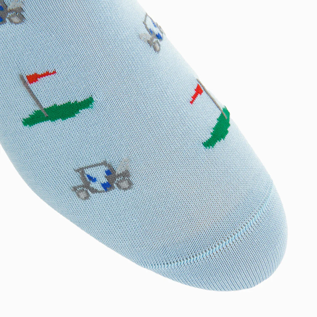 The Dapper Classics Golf Cart Cotton Mid-Calf Sock features light blue fabric accented with embroidered golf carts and red flags on green patches, adding a playful, stylish touch to any outfit.