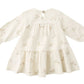 The Quincy Mae Baby Girls' and Girls' Tiered Jersey Dress is a cream-colored, long sleeve dress with a gathered skirt, subtle bunny face pattern, back button closure, and comes with matching bloomers.