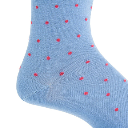 A close-up of a foot wearing a Dapper Classics Dot Mid Calf Sock, featuring blue fabric adorned with pink polka dots, made from luxurious mercerized cotton.