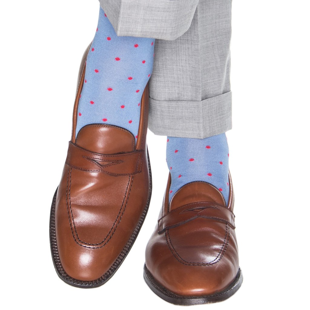 A pair of brown leather loafers accompanied by Dapper Classics Dot Mid Calf Socks in blue with pink polka dots, crafted from luxurious mercerized cotton, paired with gray trousers.