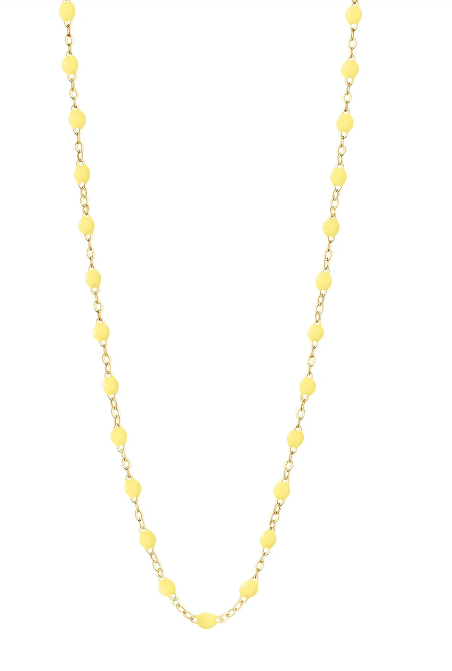 The Gigi Clozeau Classic Gigi Necklace 16.5", crafted by Gigi Clozeau from 18 carat yellow gold, showcases striking jewels and small yellow beads evenly spaced along its length against a white background.