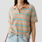 A person wearing the Short Sleeve Stripe Rugby by Guest in Residence over a layer tee, tucked into light blue jeans, with a beaded necklace.