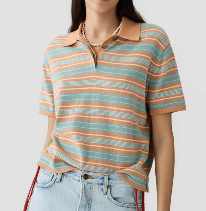 A person wearing the Short Sleeve Stripe Rugby by Guest in Residence over a layer tee, tucked into light blue jeans, with a beaded necklace.