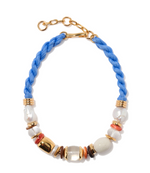 The Lizzie Fortunato Glass Beach Necklace features a blue braided cord, gold chain clasp, and an array of gold, freshwater pearls, white, and coral-colored beads.