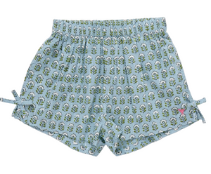 The Girls’ Jules Short by Pink Chicken showcases a Blue Prairie Blockprint adorned with a charming green and white leaf pattern, featuring an elastic waist for extra comfort, adorable side bows, and a small pink butterfly logo near the bottom hem.