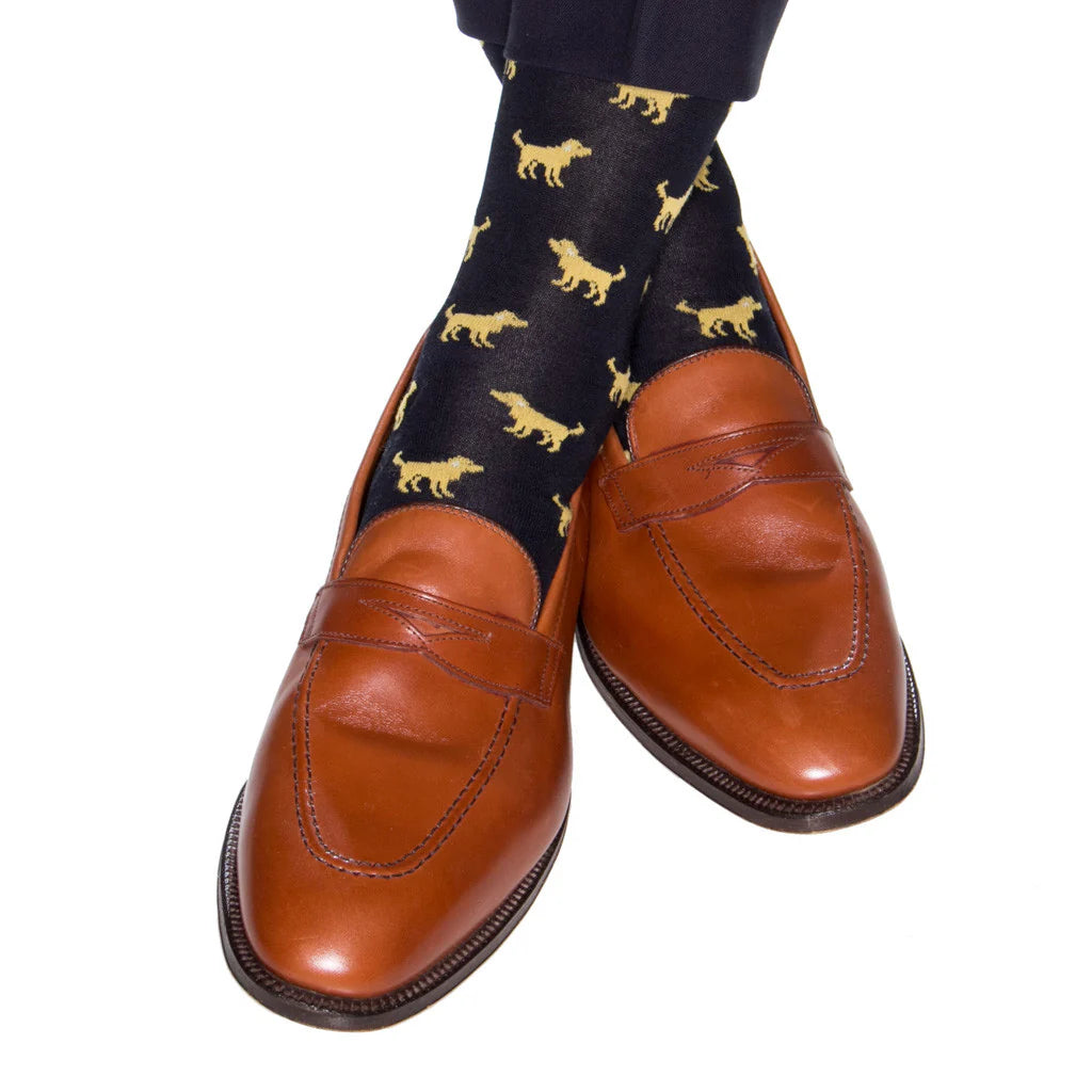 A person wearing brown leather loafers and Dapper Classics Navy with Yolk Dog Cotton Sock Linked Toe Mid-Calf socks.