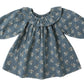 The Quincy Mae Baby Girls' and Girls' Long Sleeve Isla Dress features a blue cotton fabric with white floral print and a ruffled collar, shown on a white background.