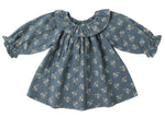 The Quincy Mae Baby Girls' and Girls' Long Sleeve Isla Dress features a blue cotton fabric with white floral print and a ruffled collar, shown on a white background.