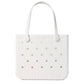 The Baby Bogg® Bag by Bogg Bags is a white tote featuring two handles, signature perforated holes on the front, and “bogg” embossed near the bottom right corner. This easy-to-clean bag combines style and practicality, allowing you to personalize it for your individual look.
