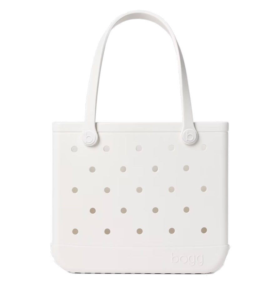 The Baby Bogg® Bag by Bogg Bags is a white tote featuring two handles, signature perforated holes on the front, and “bogg” embossed near the bottom right corner. This easy-to-clean bag combines style and practicality, allowing you to personalize it for your individual look.