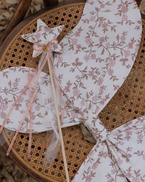 A Noralee Crown + Wand set, featuring a crown and matching wand, is displayed on a woven cane chair.