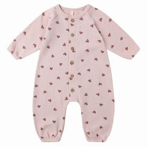 The Quincy Mae Baby Girls' Waffle Long Sleeve Jumpsuit features a light pink knit with brown heart print, front coconut buttons, and is shown on a plain white background.