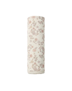 A rolled-up Swaddle by Quincy Mae, featuring a pink and brown floral pattern on beige organic brushed jersey, is positioned upright against a plain white background.