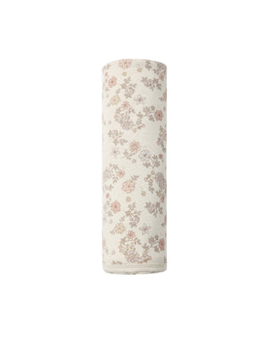 A rolled-up Swaddle by Quincy Mae, featuring a pink and brown floral pattern on beige organic brushed jersey, is positioned upright against a plain white background.