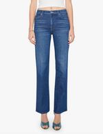 Wearing Mother's Kick It mid-blue high-rise straight-leg jeans in recycled stretch denim, a white sleeveless top, and teal open-toe heels, a person stands against a plain background.