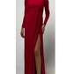 A person wears the Monique Lhuillier Jewel Neck Long Sleeve Draped Gown, a floor-length matte jersey dress with a draped bodice and high skirt slit, standing against a plain light background.